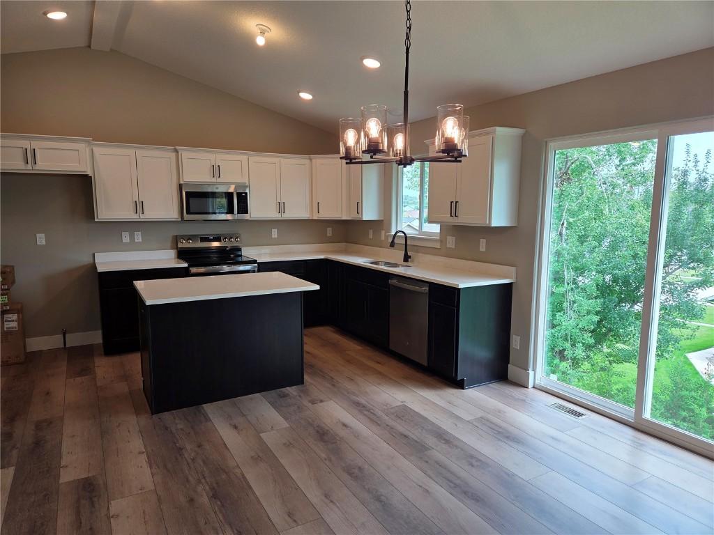 1907 Holly Meadow Ave SW, Cedar Rapids, IA 52404 - kitchen featuring stainless steel appliances, light countertops, vaulted ceiling, white cabinets, and a kitchen island