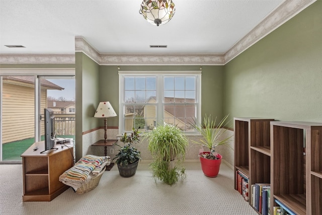 living area with carpet floors, visible vents, and crown molding