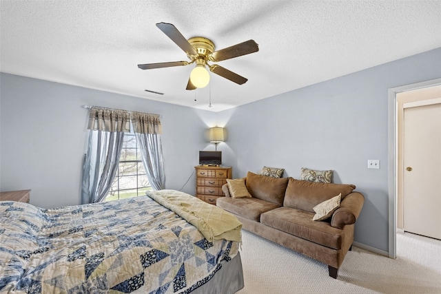 bedroom with carpet floors, a textured ceiling, baseboards, visible vents, and ceiling fan