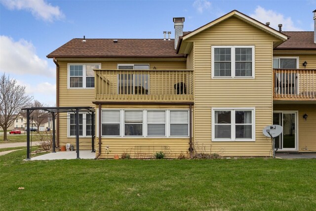 back of property with a balcony, a patio, a chimney, a lawn, and a pergola