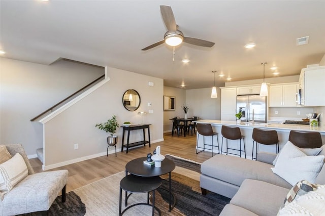 7014 C St SW, Cedar Rapids, IA 52404 - living area with light wood finished floors, stairs, ceiling fan, baseboards, and recessed lighting