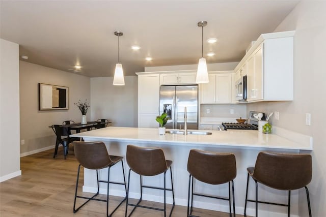 7014 C St SW, Cedar Rapids, IA 52404 - kitchen featuring appliances with stainless steel finishes, a peninsula, light countertops, white cabinetry, and light wood-style floors