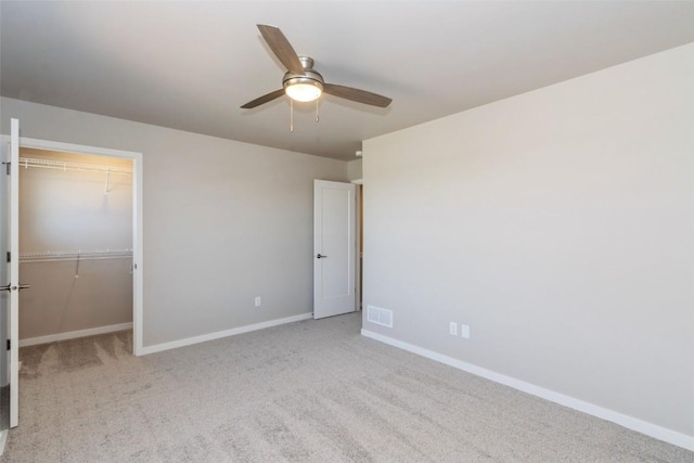 7014 C St SW, Cedar Rapids, IA 52404 - unfurnished bedroom featuring baseboards, light carpet, a closet, a walk in closet, and a ceiling fan