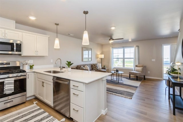 7014 C St SW, Cedar Rapids, IA 52404 - kitchen featuring stainless steel appliances, a sink, open floor plan, a peninsula, and white cabinets
