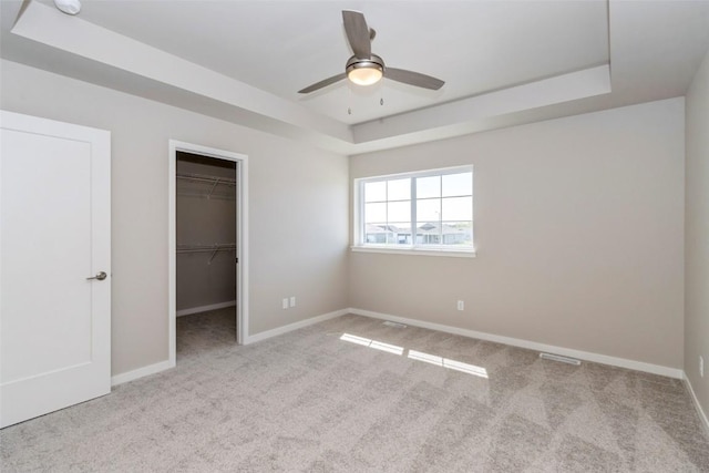 7014 C St SW, Cedar Rapids, IA 52404 - unfurnished bedroom featuring a raised ceiling, carpet, a walk in closet, and baseboards