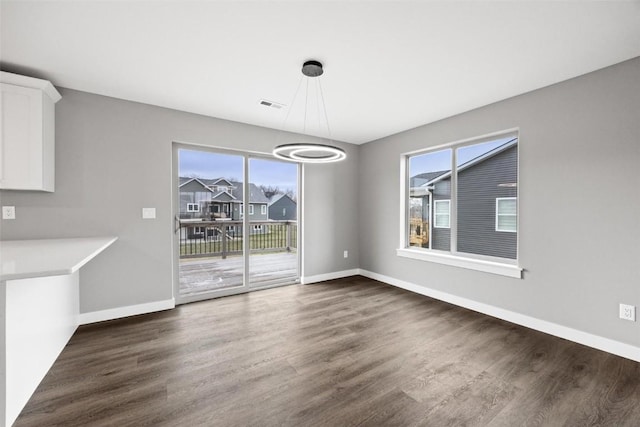 unfurnished dining area featuring dark wood-style floors, visible vents, and baseboards