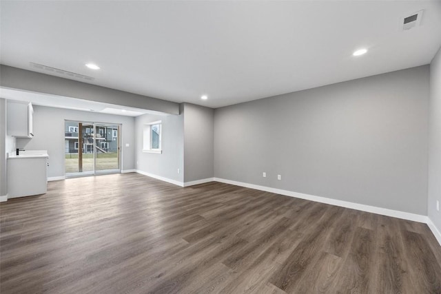 unfurnished living room with baseboards, visible vents, recessed lighting, and dark wood-type flooring