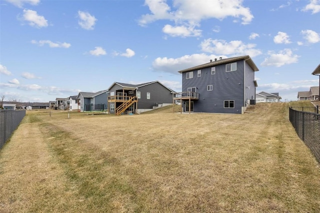 rear view of property with a lawn, a wooden deck, and a fenced backyard