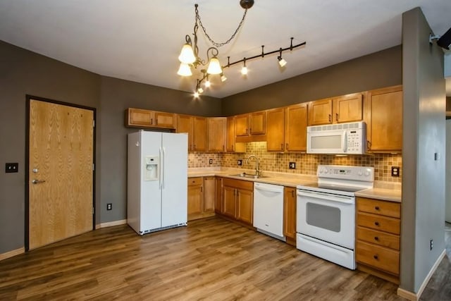 kitchen with light countertops, white appliances, an inviting chandelier, backsplash, and a sink