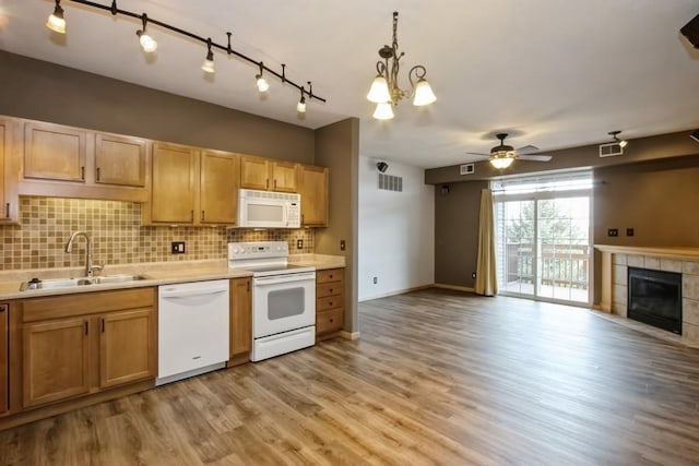 kitchen with decorative backsplash, light wood finished floors, white appliances, a sink, and open floor plan