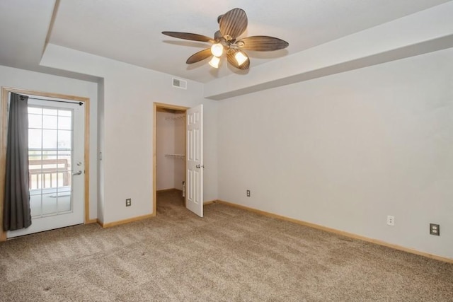 unfurnished bedroom featuring visible vents, baseboards, ceiling fan, light carpet, and a spacious closet