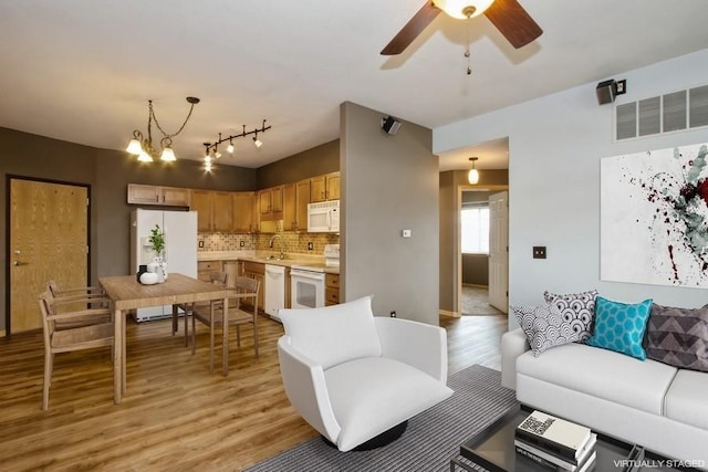 living room with a ceiling fan, light wood finished floors, and visible vents