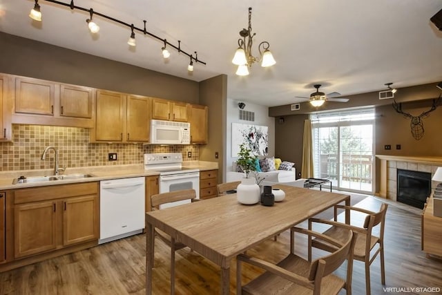 kitchen featuring decorative backsplash, a sink, light wood-type flooring, and white appliances
