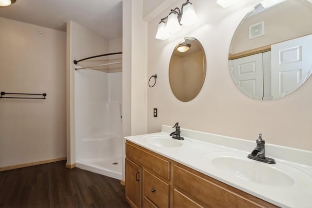 full bath with a sink, visible vents, walk in shower, and wood finished floors