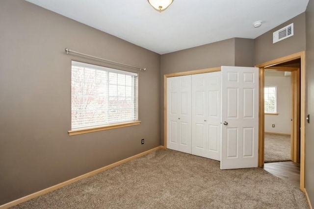 unfurnished bedroom with baseboards, carpet, a closet, and visible vents