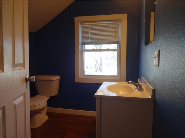 549 Marengo Ave, Marengo, IA 52301 - bathroom featuring vanity, baseboards, vaulted ceiling, toilet, and wood finished floors