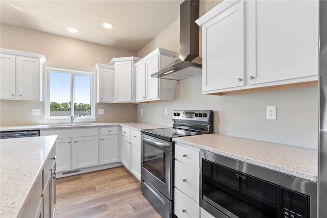kitchen featuring stainless steel appliances, wall chimney range hood, a sink, white cabinets, and recessed lighting