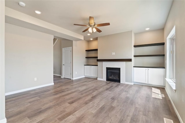 1306 E Gable Way, Tiffin, IA 52340 - unfurnished living room featuring a ceiling fan, baseboards, wood finished floors, a glass covered fireplace, and recessed lighting