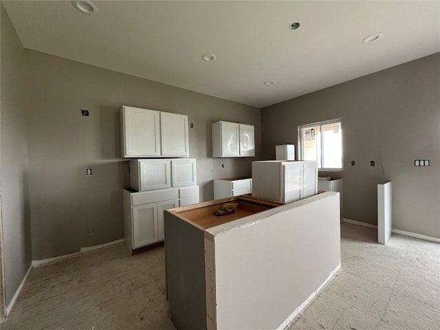 1306 E Gable Way, Tiffin, IA 52340 - kitchen with white cabinets, baseboards, a center island, and recessed lighting