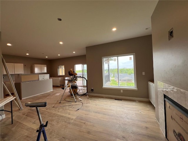 1306 E Gable Way, Tiffin, IA 52340 - exercise area featuring a tiled fireplace, recessed lighting, light wood-style floors, and baseboards