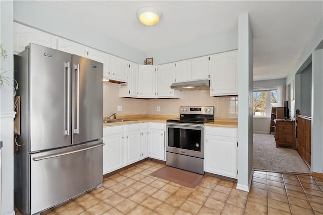 kitchen with white cabinets, under cabinet range hood, light countertops, and appliances with stainless steel finishes