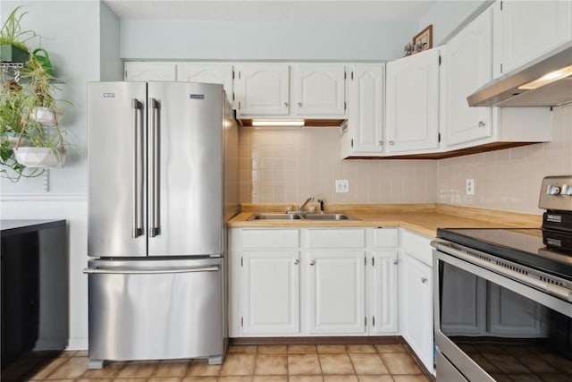 kitchen featuring under cabinet range hood, decorative backsplash, a sink, and stainless steel appliances