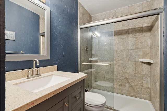 full bath featuring a textured wall, vanity, a stall shower, and toilet