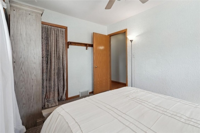 bedroom featuring a closet, a textured wall, ceiling fan, and visible vents