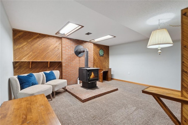 living room with wooden walls, a wood stove, carpet, and baseboards