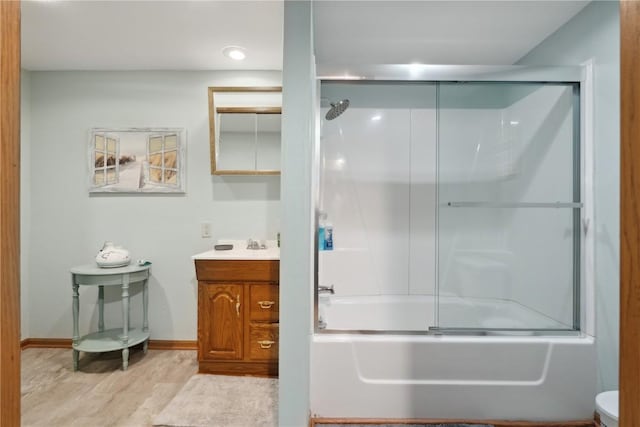 full bath with bath / shower combo with glass door, vanity, baseboards, and toilet