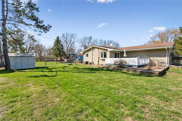 back of house with a shed, a yard, fence, an outbuilding, and a wooden deck