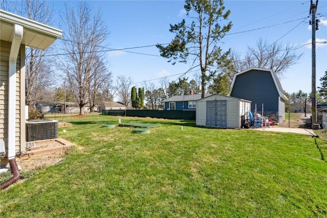 view of yard with a shed, central AC, fence, and an outbuilding