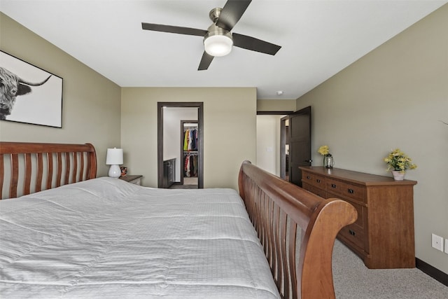 bedroom featuring a spacious closet, a ceiling fan, a closet, and carpet