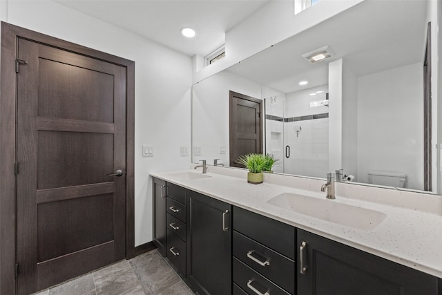 full bathroom featuring toilet, double vanity, a sink, and a shower stall