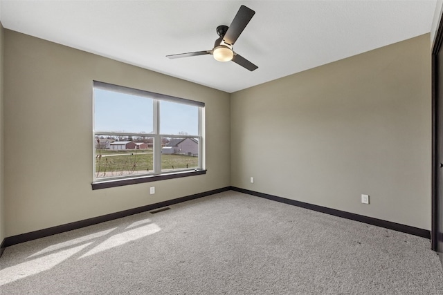 spare room with baseboards, visible vents, light carpet, and ceiling fan