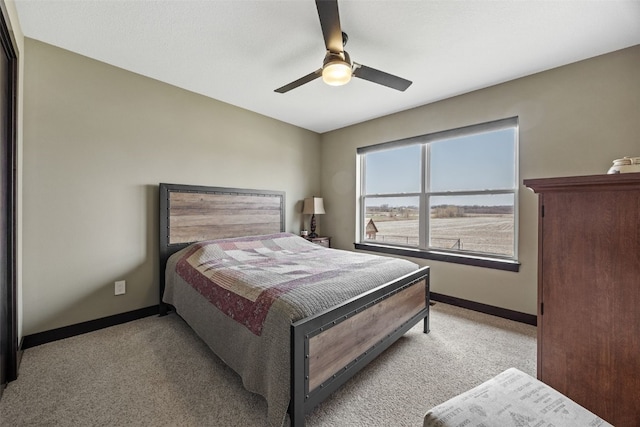 bedroom with a ceiling fan, light colored carpet, and baseboards
