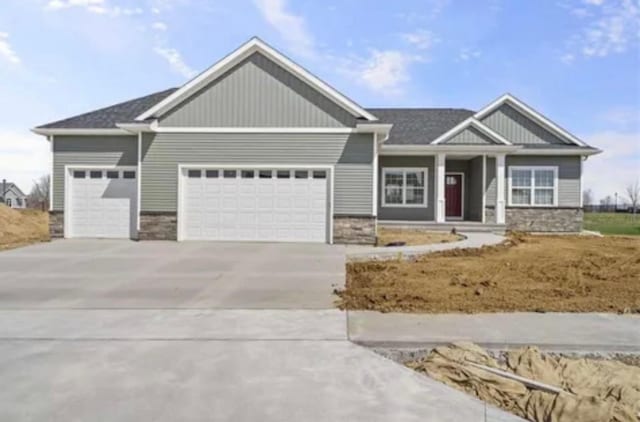 craftsman-style home with stone siding, a garage, and concrete driveway