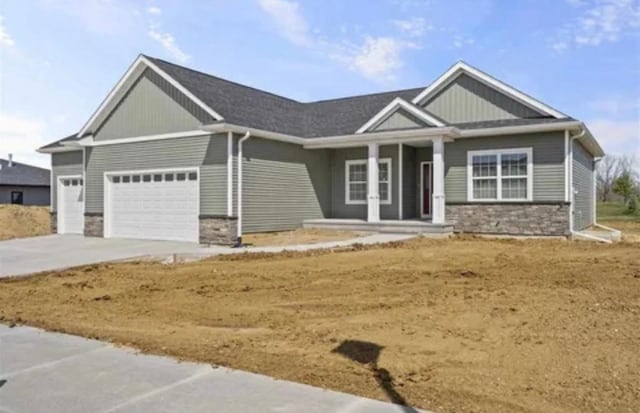 craftsman-style home featuring board and batten siding, driveway, stone siding, and a garage