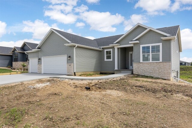 1442 Cardinal Dr, Fairfax, IA 52228 - view of front of property with an attached garage, stone siding, driveway, and a shingled roof
