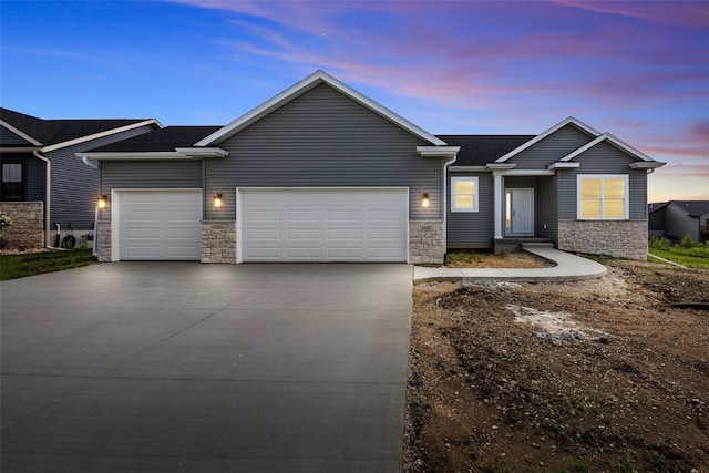 1442 Cardinal Dr, Fairfax, IA 52228 - view of front of house with a garage, stone siding, driveway, and roof with shingles