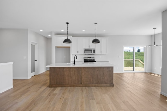 1442 Cardinal Dr, Fairfax, IA 52228 - kitchen with stainless steel appliances, light wood finished floors, white cabinets, light countertops, and an island with sink