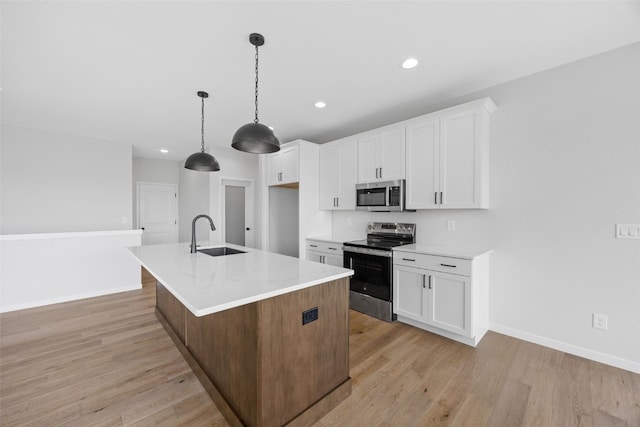 1442 Cardinal Dr, Fairfax, IA 52228 - kitchen featuring appliances with stainless steel finishes, light wood-style flooring, white cabinets, light countertops, and a center island with sink