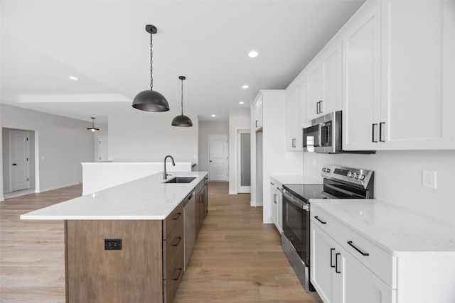 1442 Cardinal Dr, Fairfax, IA 52228 - kitchen featuring appliances with stainless steel finishes, recessed lighting, a kitchen island with sink, white cabinets, and light wood-type flooring