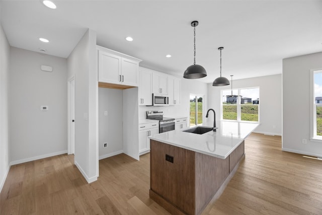 1442 Cardinal Dr, Fairfax, IA 52228 - kitchen featuring stainless steel appliances, light wood finished floors, a kitchen island with sink, white cabinets, and recessed lighting