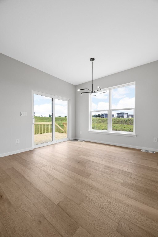 1442 Cardinal Dr, Fairfax, IA 52228 - unfurnished room with a chandelier, wood finished floors, and healthy amount of natural light