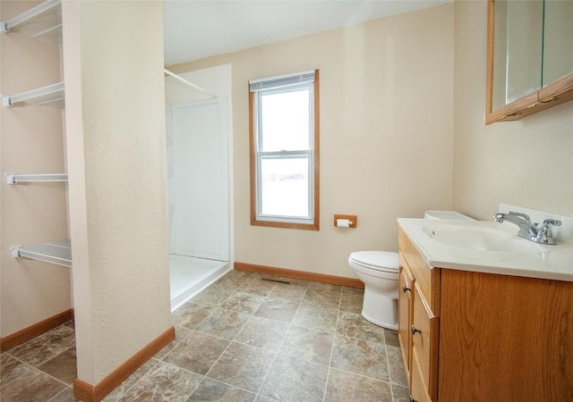 110 SE 12th St, Oelwein, IA 50662 - full bathroom featuring toilet, baseboards, a walk in shower, and vanity