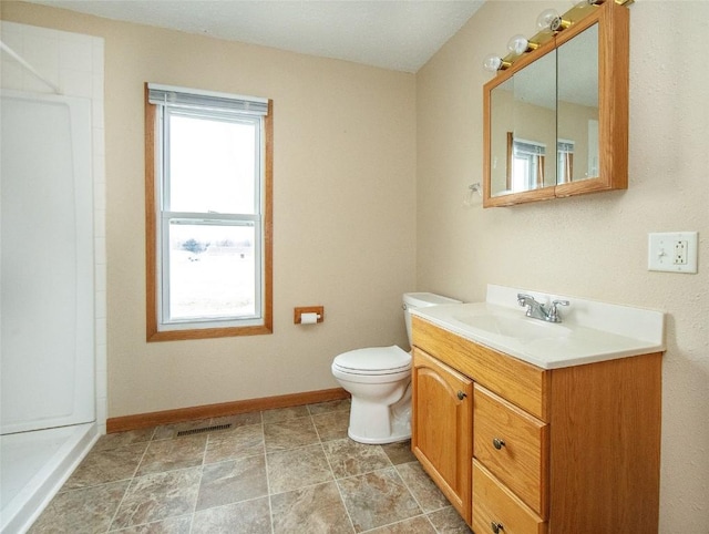 110 SE 12th St, Oelwein, IA 50662 - bathroom with vanity, baseboards, walk in shower, toilet, and visible vents