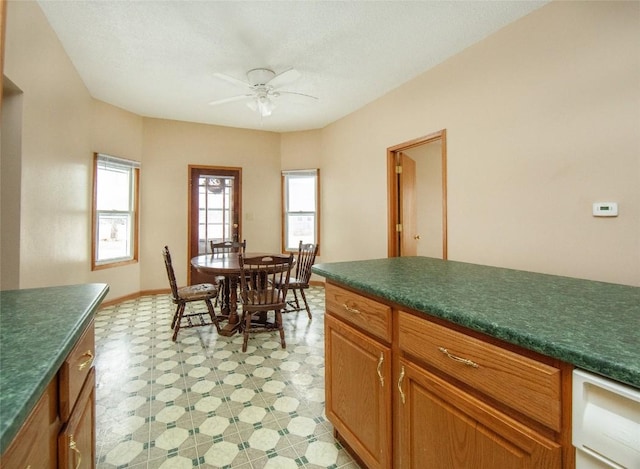 110 SE 12th St, Oelwein, IA 50662 - kitchen featuring baseboards, dark countertops, light floors, and a ceiling fan