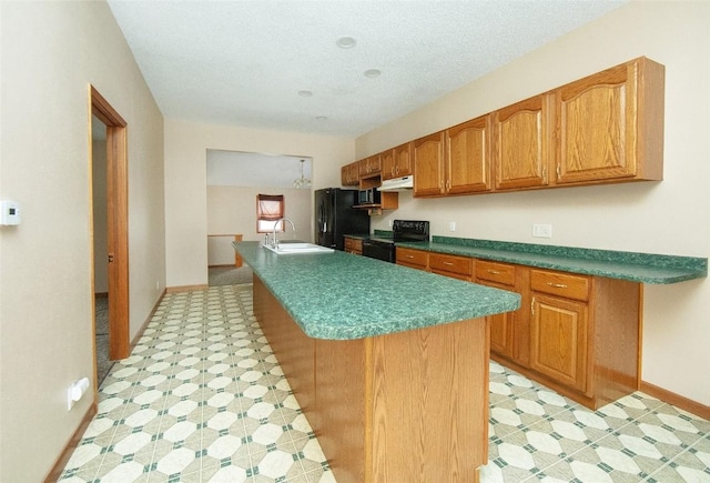 110 SE 12th St, Oelwein, IA 50662 - kitchen featuring an island with sink, light floors, black appliances, under cabinet range hood, and a sink