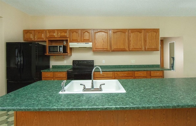 110 SE 12th St, Oelwein, IA 50662 - kitchen with black appliances, under cabinet range hood, a sink, dark countertops, and brown cabinets
